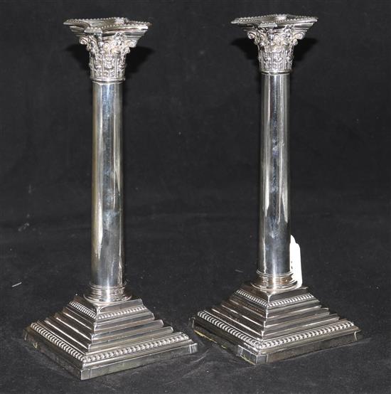 A pair of late Victorian silver corinthian column candlesticks with plain stems by Maurice Krumm, London, 1894, weighted.